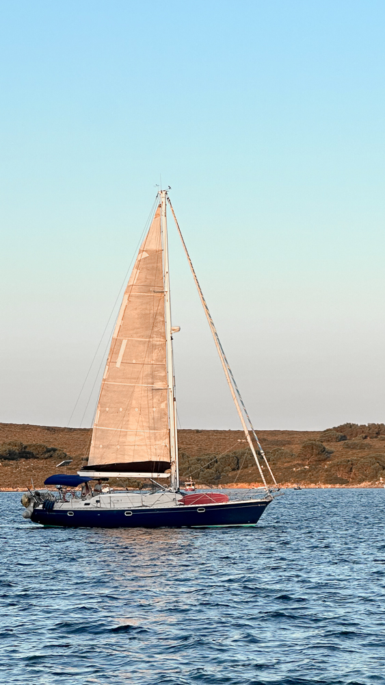 Barca a vela al tramonto tra le scogliere di Fornells, Minorca